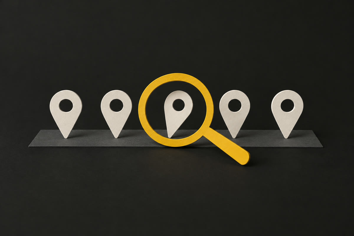 Illustration of off-white paper map pins in a row on charcoal, with a yellow paper magnifying glass over the one that's out of line.