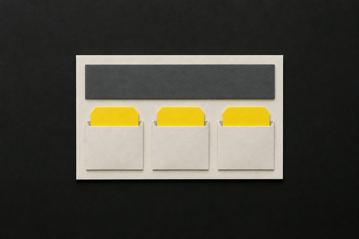 Illustration of an off-white paper listing card with yellow paper tags tucked into its lower slots and a bare grey strip on top, on charcoal.