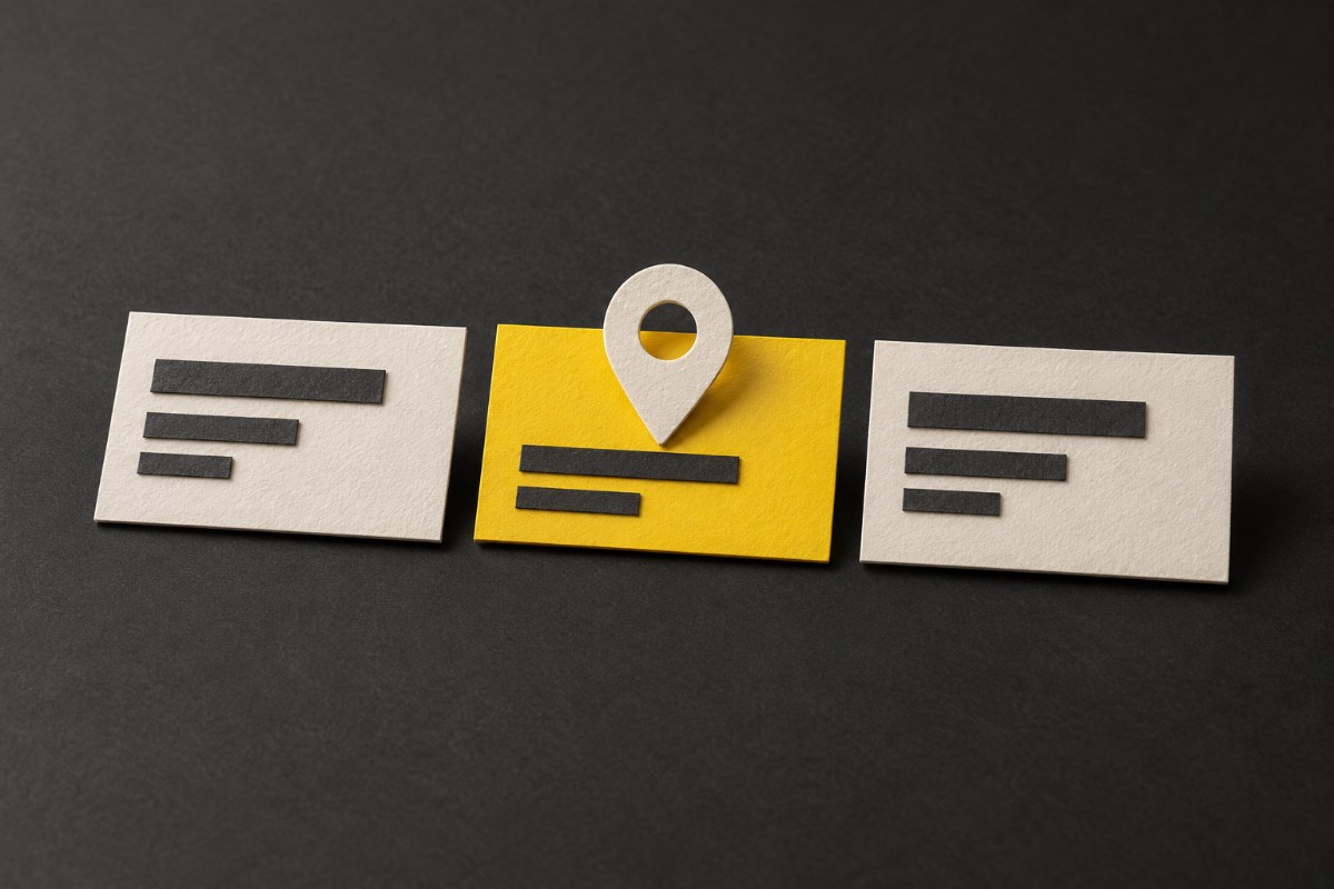 Illustration of three paper business cards on charcoal, one yellow with a map pin on it.